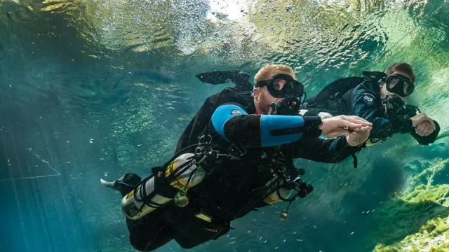A sidemount diver in trim over the reef